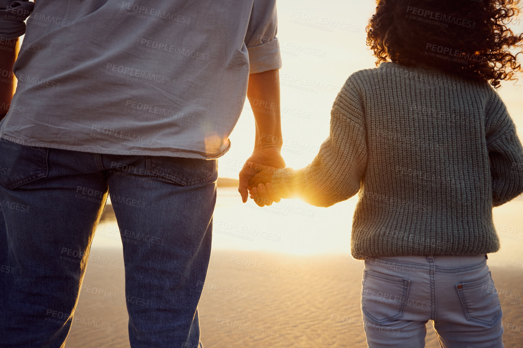 Buy stock photo Closeup of father and little girl holding hands while watching the sunset together at the beach. Dad and young daughter showing affection, love and support by holding hands