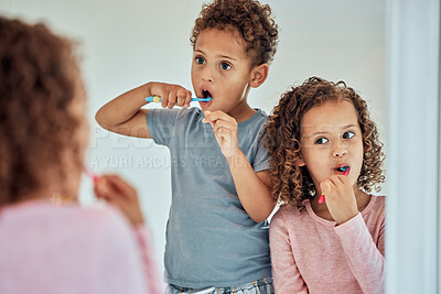 Buy stock photo Adorable little sibling brother and sister brushing their teeth while looking in the bathroom mirror. Little girl and boy practising good oral hygiene. Brushing twice a day is important
