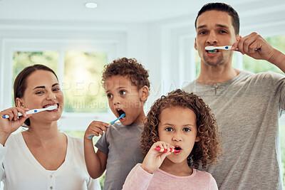 Buy stock photo Happy mixed race parents and their two children brushing their teeth together at home. Young couple teaching their kids good hygiene habits. Family of four with little girl and boy getting ready together