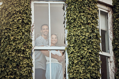 Buy stock photo Happy young mixed race couple standing in their window. Loving couple bonding and spending time together at home.  Lovers standing by a window with leaves growing up the exterior wall. Warm and cozy at home 