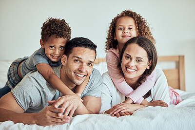 Buy stock photo Portrait of happy family with little kids lying on the bed at home. Smiling couple bonding with their son and daughter in the morning at home. Adorable boy and girl lying on their mother and father