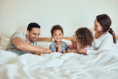 Buy stock photo Mixed race Family lying in bed smiling and playing. Latino parents having fun with their little cute kids