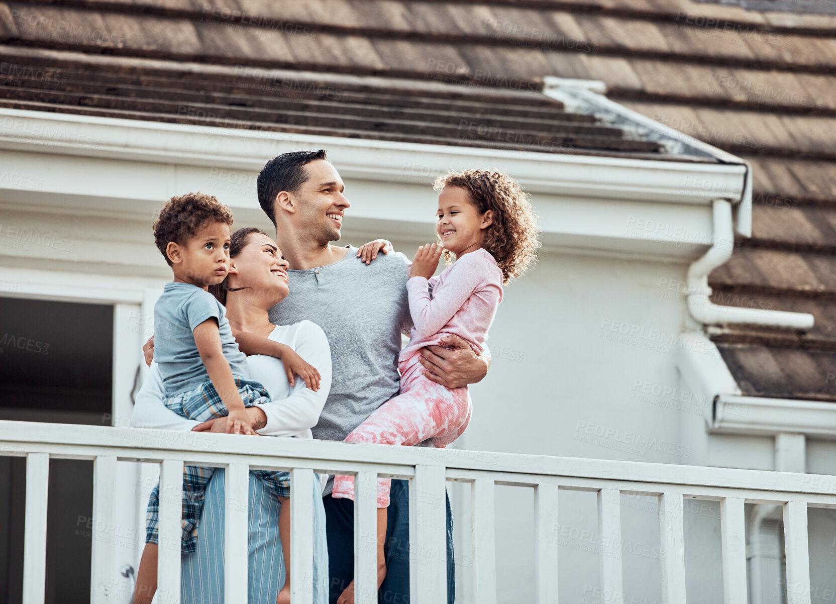 Buy stock photo Happy young mixed race family with two children standing outside on their balcony at home. Loving couple with their daughter and son wearing pyjamas and enjoying their new house