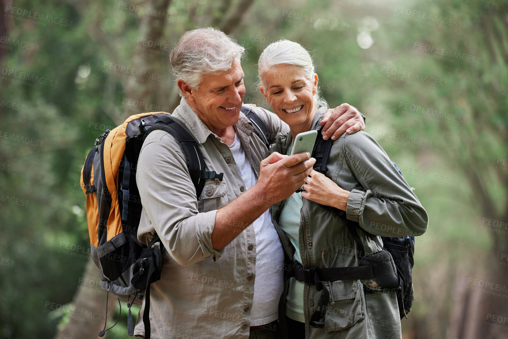 Buy stock photo Phone, video call and elderly couple hiking in a forest, happy and smile while bonding on adventure. Active seniors, online and maps for man and woman backpacking in nature while checking location