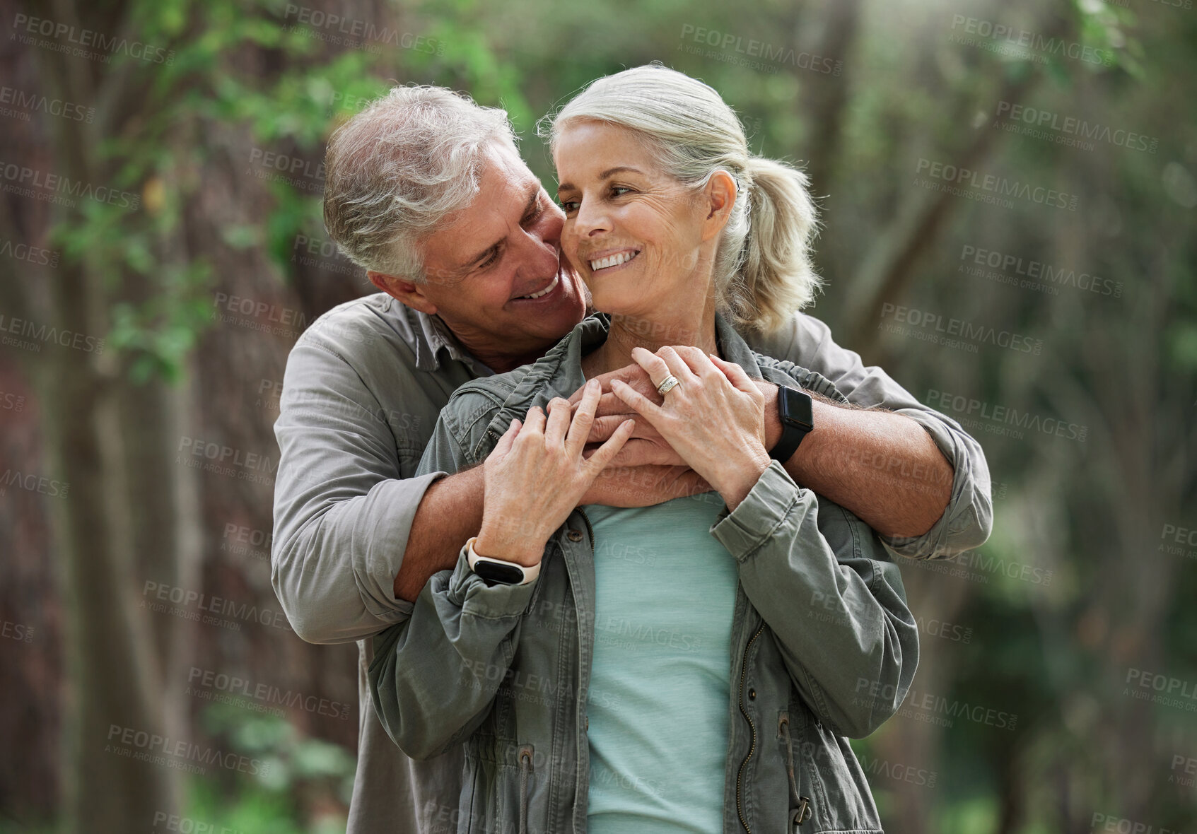 Buy stock photo Hug, hiking and senior couple in nature with smile on adventure in forest, woods and mountain for exercise. Fitness, retirement and happy elderly man and woman on trekking hike for travel wellness