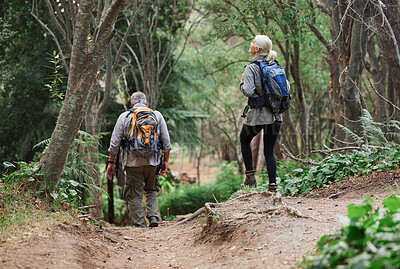 A rear view of amature caucasian couple out for a hike together. Senior man and woman exploring and walking in a forest in nature