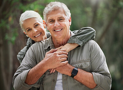 Portrait of a senior caucasian couple smiling and looking happy in a forest during a hike in the outdoors. Man and wife showing affection and holding each other during a break in nature