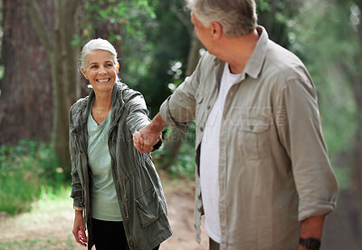 A mature couple holding hands while out hiking together. Senior couple smiling during a hike looking happy in nature
