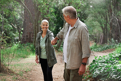 A mature couple holding hands while out hiking together. Senior couple smiling during a hike looking happy in nature