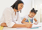 Mixed race mother helping her daughter with her homework. Mom teaching daughter to read and write during homeschool class. Little girl sitting at home with tutor