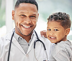 Portrait of handsome young black paediatrician holding adorable little boy in hands, cute child and doctor smiling during medical check up in clinic