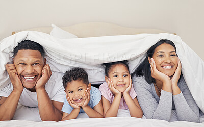 Buy stock photo Portrait of happy family with two children lying under duvet smiling and looking at camera. Little girl and boy lying in bed with their parents bonding and having fun
