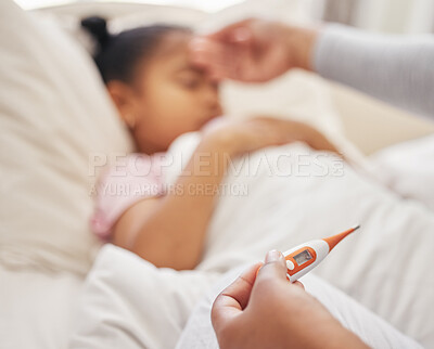 Sick little girl in bed while her mother uses a thermometer to check her temperature. Mixed race parent feeling daughter\'s forehead. Hispanic child feeling ill and sleeping while mother checks fever