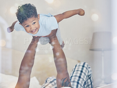 Happy little mixed race boy flying in fathers arms looking at camera in bedroom. Dad holding and lifting cute little child playing and having fun on bed