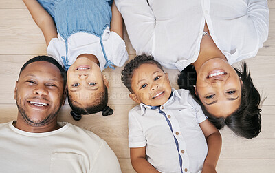 Buy stock photo Happy mixed race family with two children lying on floor together and bonding at home from above. Little brother and sister spending time with their parents