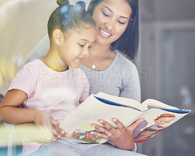 Loving hispanic mother reading to adorable little daughter at home. Cute girl sitting on mothers lap while reading story book together and bonding at home