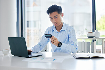 Closeup of one young asian businessman spending money online with a credit card and phone in an office. Making purchase transaction with secure banking payment. Budgeting finance for bills and e-commerce shopping
