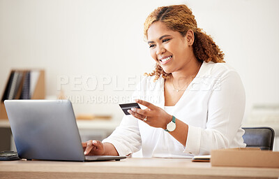 Mixed race happy businesswoman using a credit card and working on a laptop to shop online at work. Hispanic woman paying for a purchase. Female making payment using a laptop and bank card
