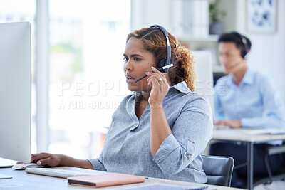 One stressed and confused mixed race call centre telemarketing agent talking on a headset while working on a computer in an office. Young shocked african american female consultant dealing with panic crisis and difficult caller for customer support