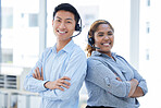 Portrait of two happy smiling diverse call centre telemarketing agents standing back to back with arms crossed while wearing headset in an office. Confident and friendly african american and asian assistants providing customer service support