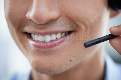 Closeup of one happy call centre telemarketing agent with big smile talking on headset while working in office. Face of confident friendly businessman operating helpdesk for customer service and sales support
