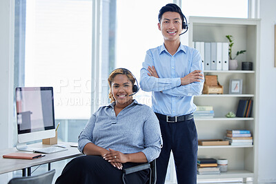 Portrait of two happy smiling diverse call centre telemarketing agents wearing headsets while working in an office. Confident and friendly african american and asian assistants operating helpdesk for customer service support