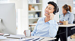 One young asian call centre agent talking on a headset while working on computer in an office. Confident and happy business consultant operating a help desk for customer sales and service support