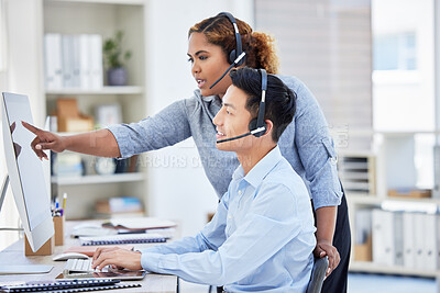 African american call centre agent training new asian assistant on an office computer. Smiling customer service businessman sitting and getting help from mixed race woman. Coaching and teaching intern
