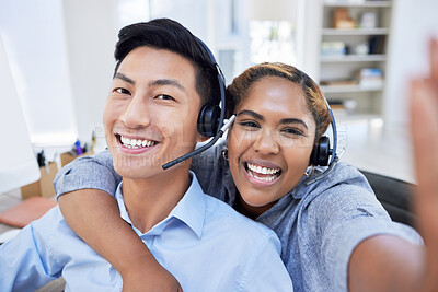 Portrait of call center colleagues taking a selfie showing diversity at the workplace. Business People working customer service wearing headsets and smiling while training to be sales rep. Asian male and hispanic female looking happy