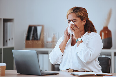 Buy stock photo Sick mixed race businesswoman blowing her nose with a tissue while working on a laptop in an office alone at work. Ill woman blowing her nose. Hispanic businessperson with a cold blowing their nose
