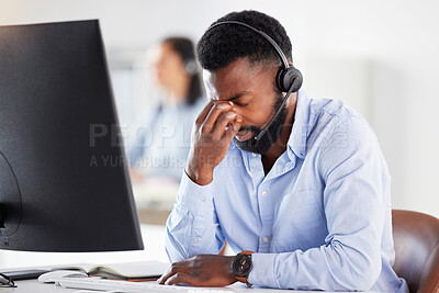 Buy stock photo Mental health, man call center agent with headache and headset with computer at his desk in a modern workplace office. Telemarketing or consultant, stress or burnout and male person at workspace