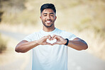 Portrait happy fit young mixed race man making a heart shape with his hands while exercising outdoors. Handsome indian man showing that he loves to work out, stay healthy and run outside in nature