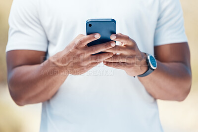 Closeup of a mixed race unknown male using his smartphone outside before a workout. Unknown ethnic male send a text using his wireless device outdoors