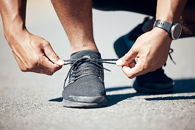 Closeup view of an unrecognisable man tying his shoelaces while exercising outdoors. Unknown male tying his laces before a run outside