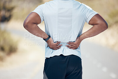 Rear view of a unknown man standing alone and suffering from backache during his outdoor workout. Mixed race male having tension in his joints during a workout in nature