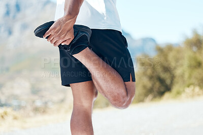 Closeup of an unknown man standing alone and stretching during his outdoor workout. Fit male warming up before a run outside