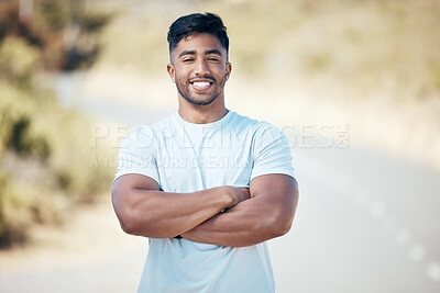 Portrait of a young mixed race man looking proud standing with his arms crossed in the road after exercising outside. Indian male smiling and feeling satisfied with his daily workout