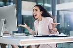 Young happy mixed race businesswoman looking shocked and amazed using a desktop computer in an office. One cheerful hispanic businessperson smiling making a hand gesture while looking at a pc screen at work