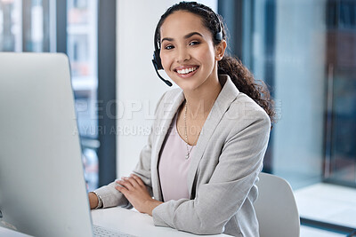 Portrait of smiling mixed race call center agent using a computer in an office. Hispanic customer care assistant wearing headset and answering calls from clients. Ambitious salesperson calling customer