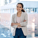 Portrait of a happy mixed race businesswoman standing with her arms crossed alone in her office. One hispanic businesswoman feeling confident standing at work. Female boss working as an entrepreneur
