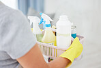 One unrecognizable woman holding cleaning supplies while cleaning her apartment. An unknown domestic cleaner wearing latex cleaning gloves and a collection of products
