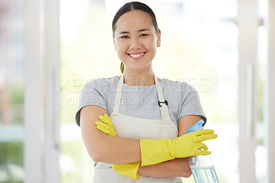 One smiling mixed race woman cleaning her apartment. Young Asian domestic worker smiling while cleaning and wearing rubber gloves