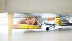 A mixed race domestic worker looking while lying on the floor and cleaning under the sofa. One mixed race female using a vacuum cleaner under a couch to begin spring cleaning