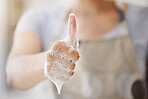 An unrecognizable woman with foam covered hands showing the thumbs up gesture. One unknown woman cleaning her fingers and promoting healthy habits and daily care