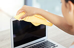 An unrecognizable woman cleaning her laptop in her apartment. One unknown woman using a rag to remove dust from her laptop keyboard