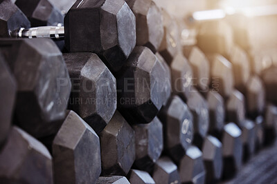 Closeup of stacked and piled heavy dumbbell weights arranged in empty gym with nobody during day. Weightlifting equipment organised in groups in health and sports centre with no one. Healthy routine