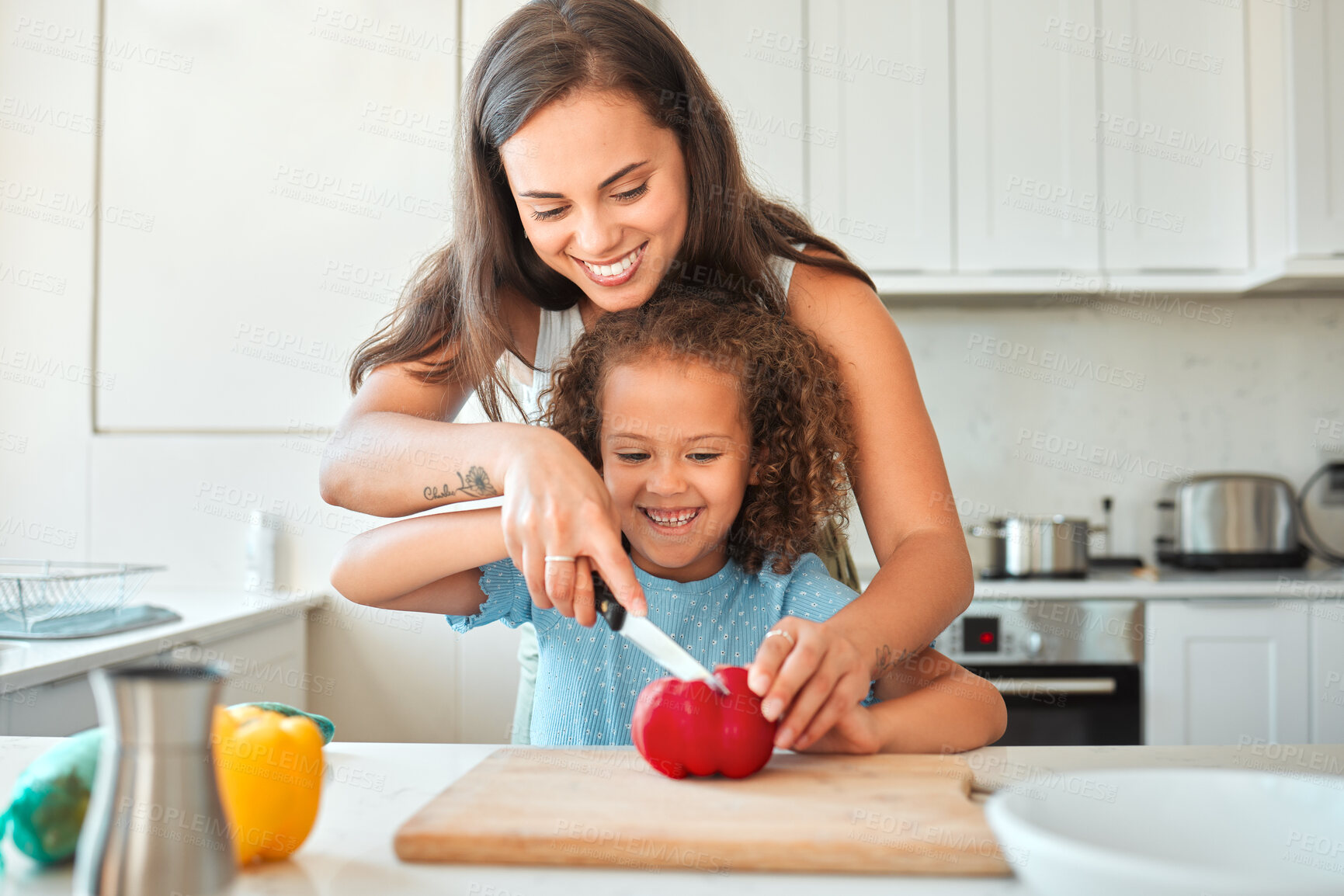 Buy stock photo Loving mother and small daughter chopping vegetables and preparing vegetarian meal in the kitchen at home. Little girl using knife with the help of mom