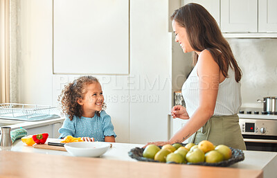 Mother and little daughter talking while mom teach her how to cook a vegetarian meal. Cooking with a little helper