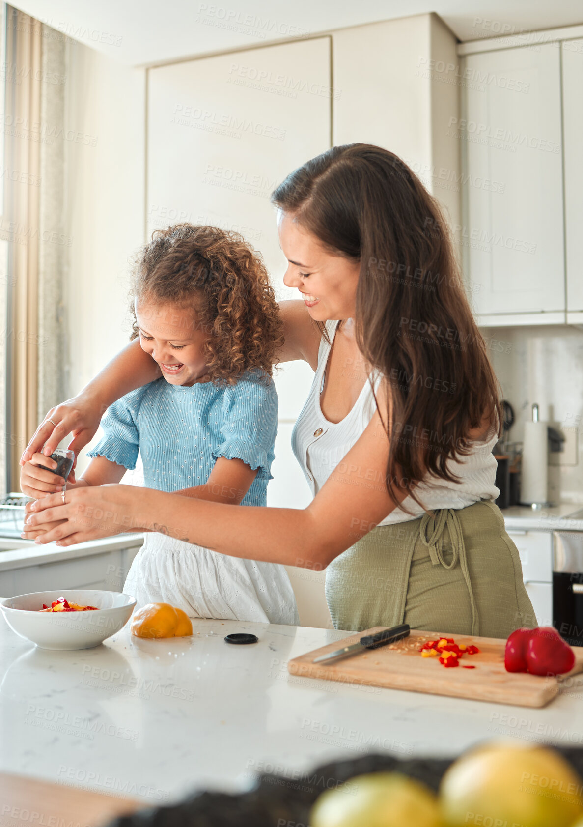 Buy stock photo Happy mother teaching little daughter to cook in kitchen at home. Little girl adding seasoning pepper grinder to a bowl while making a salad with mom