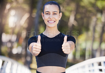 Happy female athlete showing thumbs up with both hands while out for a run or jog outdoors. Fit young woman smiling and looking satisfied during her workout at the park